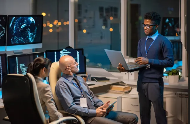 Three people working together in an office at night